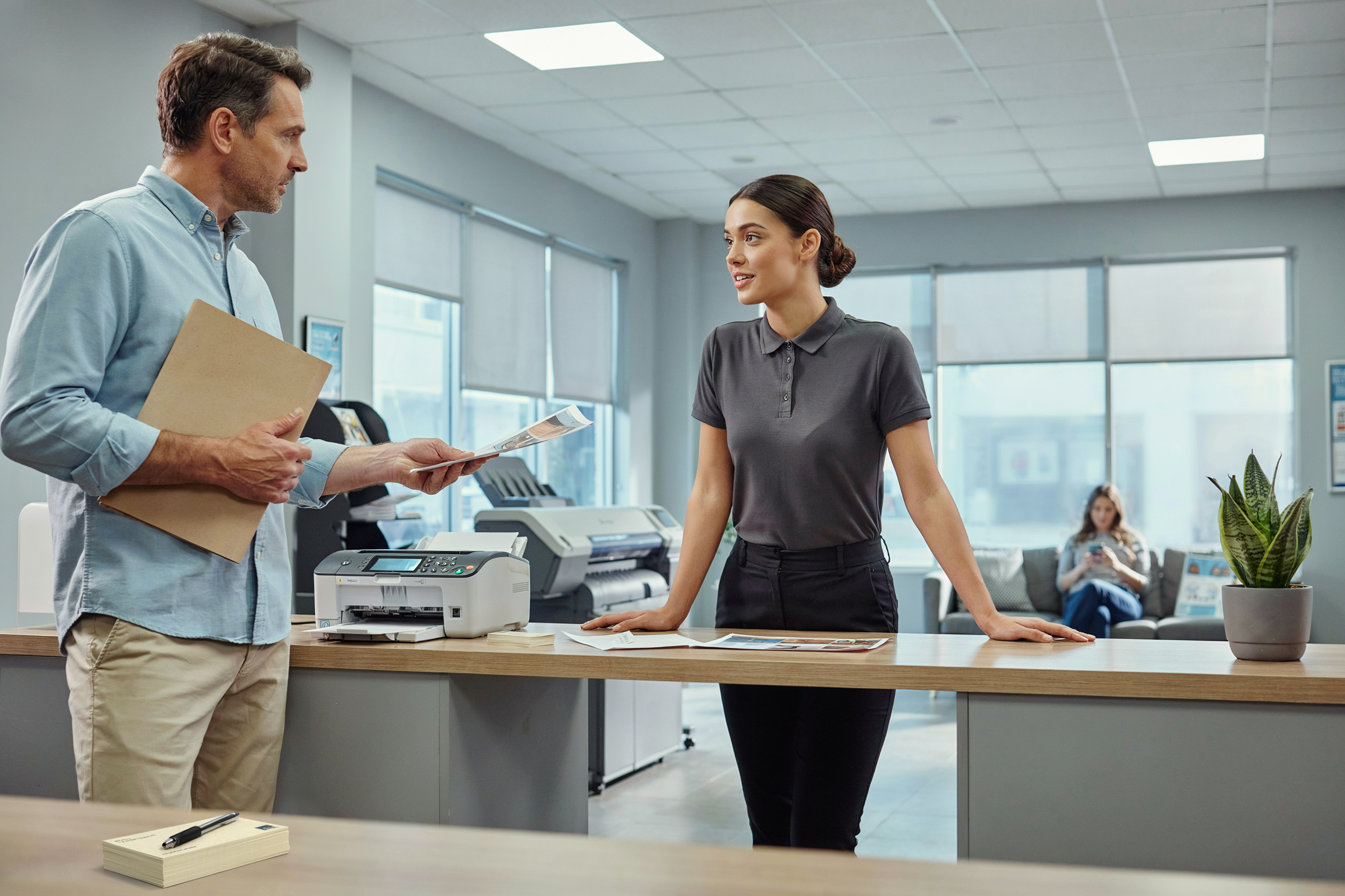 copy shop counter with a small fax machine visible, a clerk assisting a customer